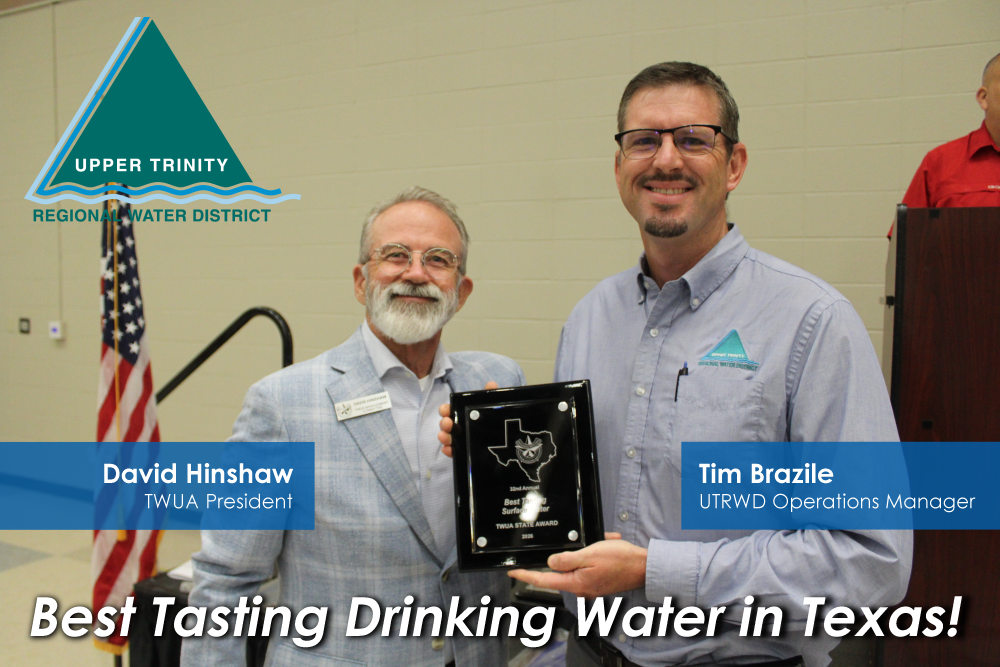 Two men smile during an award presentation: one holds a framed plaque, with the Upper Trinity Regional Water District logo and an American flag nearby; caption reads 'Best Tasting Drinking Water in Texas!'