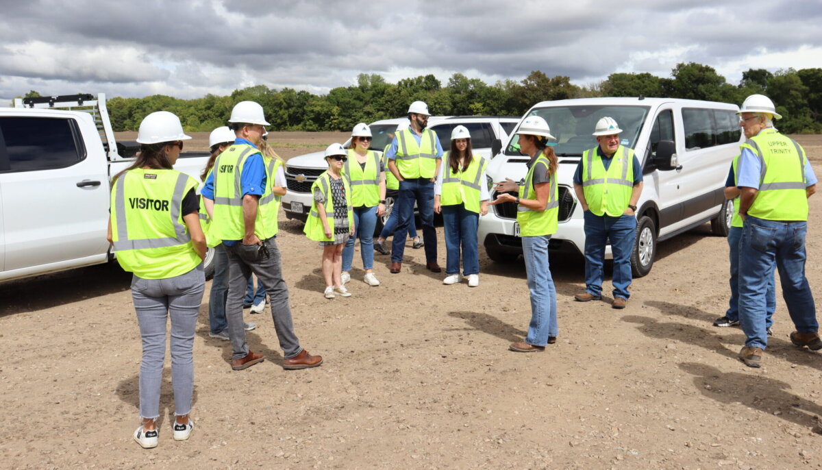 Members of Texas Water Development Board and Texas Water Conservation Association listen to a project update in front of vehicles onsite at Lake Ralph Hall.